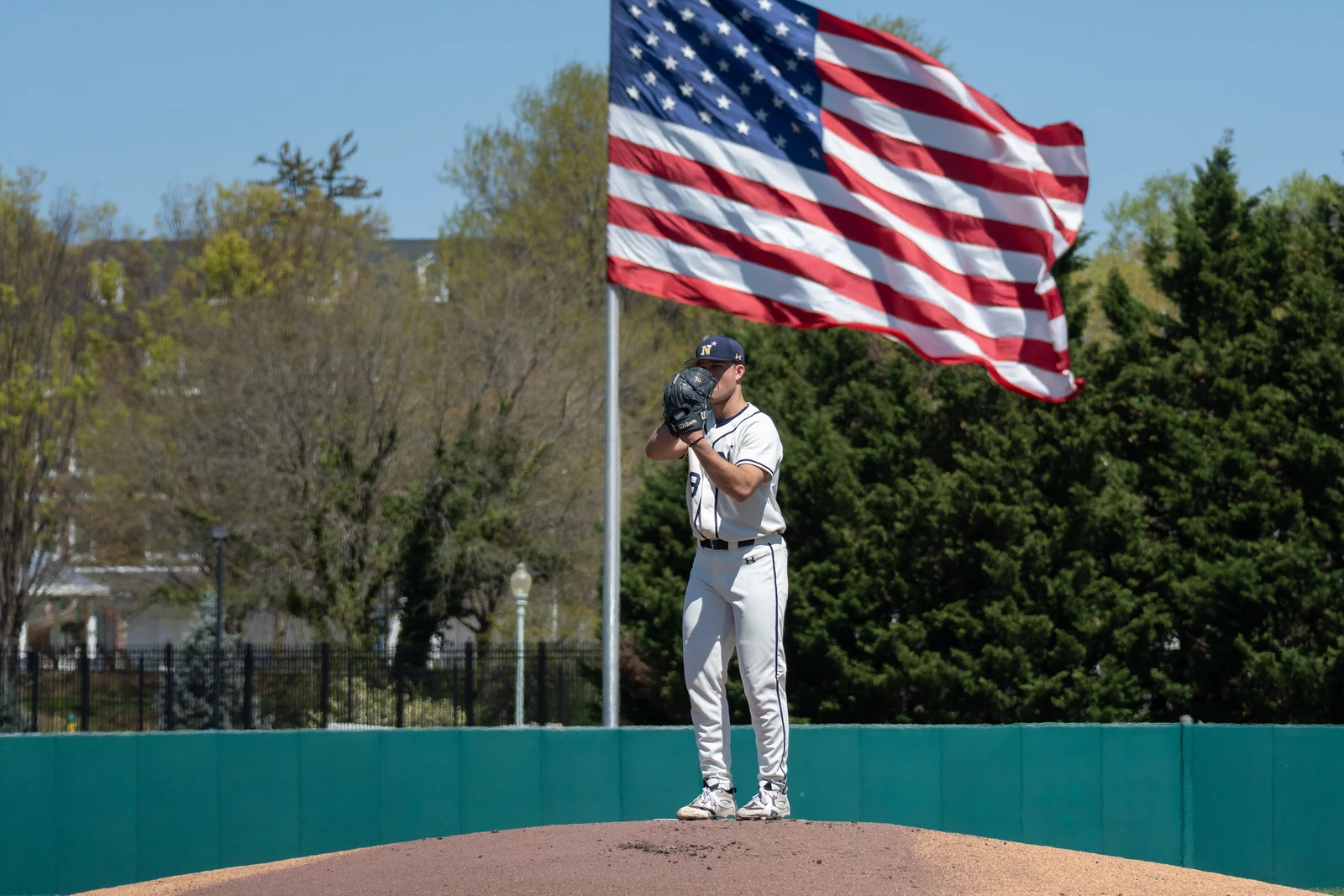 Navy pitcher set on the mound beneath the American flag