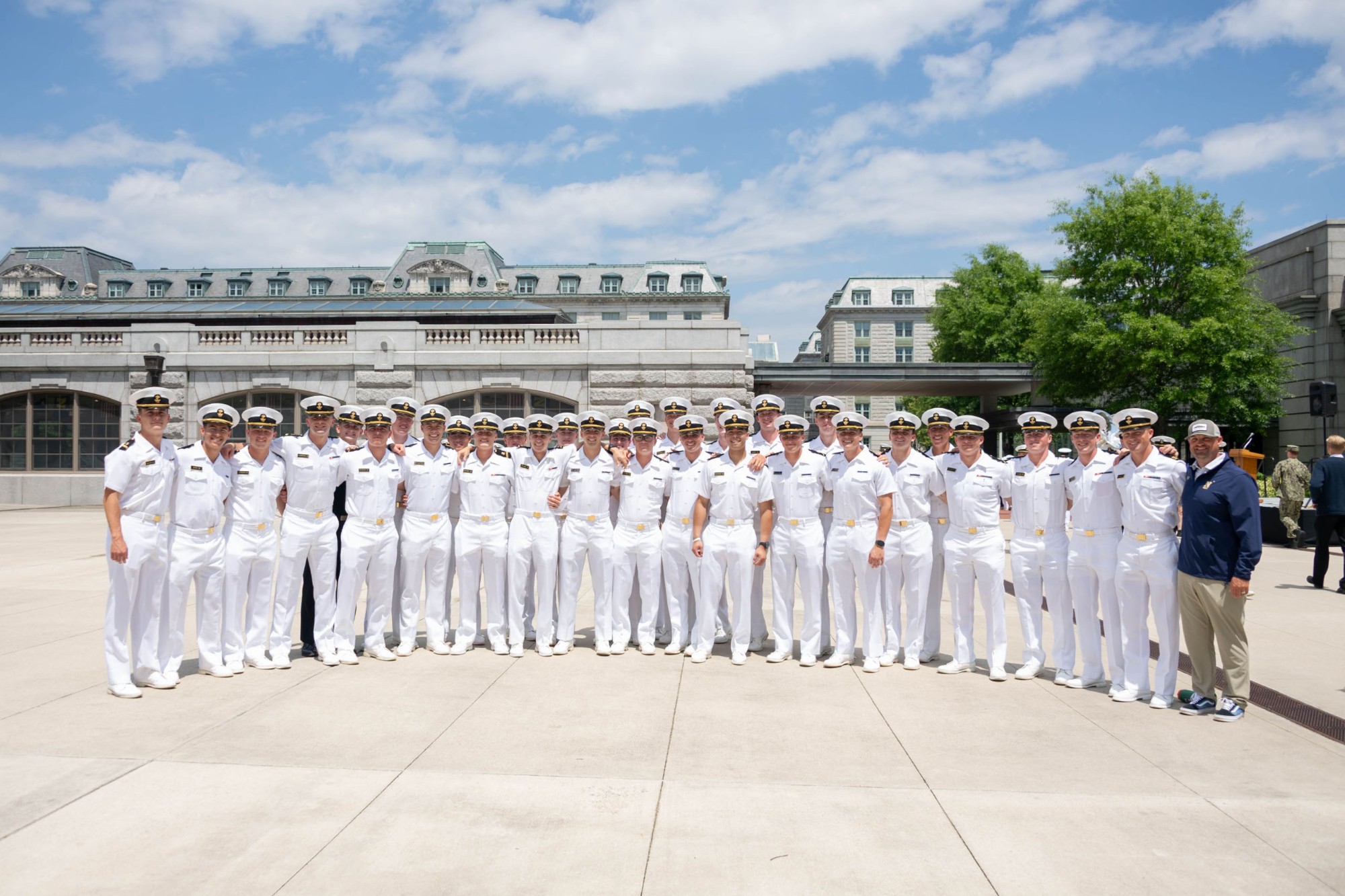 Navy baseball players in dress whites in front of Bancroft Hall